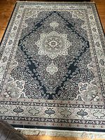 Photo of the full flatweave area rug showing the detailed floral medallion design and border with fringes at the edge.