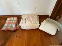 View of all four items folded and displayed: pastel plaid wool blanket, beige quilted Nygard queen electric duvet cover, and two soft beige blankets.