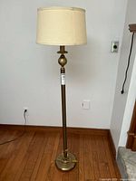 Full view of a 60-inch tall floor lamp with a brushed brass-like base and cream-colored lampshade, showing overall condition and styling.