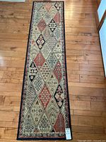 Full view of 22x87 hallway runner with diamond patchwork pattern and floral motifs on wood flooring.