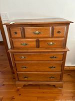Front view of the maple highboy showing drawer fronts and brass hardware.
