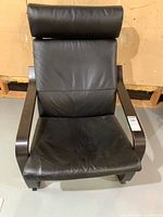 Front view of the Ikea Poang chair with leather seat and headrest.