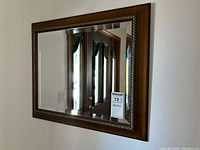 Clear view of the wall mirror with wooden frame measuring 24x20 inches, showing the carved rope-like pattern on the frame and reflection of indoor doorway.