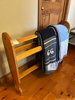Wooden quilt rack with quilt draped over, showing side view and decorative etchings