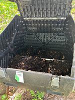Open top view of the rotating composter showing interior with compost material inside and locking latches on the front.