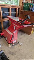 Overall view of the red Troy-Bilt chipper shredder attachment showing the hopper, handle, and base