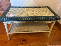 Front angled view of wicker coffee table showing cream woven shelf below and green bordered top.