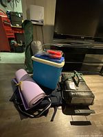 Overview of all camping gear including cooler, portable grill, sleeping bag, chair, air pump, yoga mat, and lantern