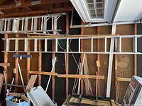 Long view of the aluminum extension ladder leaned against a wall, showing full length and general condition including paint splatters.
