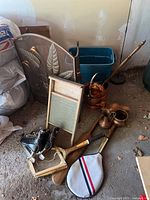 Fireplace screen with decorative metal leaves, washboard, tennis racquets, copper kettle, bed warmer, and skates arranged on floor