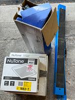 Two cardboard boxes containing NuTone ventilation fans ARN80C alongside blue Mastercraft stands.