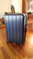 Front view of the navy blue hard sided rolling suitcase with Heys logo.