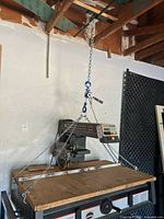 Lever chain hoist suspended from ceiling with lifting hooks and chains, showing the full assembly length and configuration.