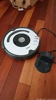 Top and side view of Roomba 670 vacuum robot with charging dock on a wooden floor.