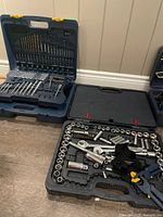 Two open blue carrying cases. One with multiple sockets and ratchet tools. The other with drill bits and screwdriver bits organized inside.