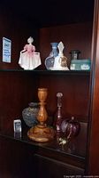 Two shelf display with Royal Doulton figurine, Wedgwood jasperware items, wooden candlestick, glass decorative objects.