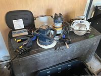 Full view of the lot showing all five main tools on top of a textured plastic cabinet: Mastercraft orbital jigsaw, Wen car waxer, Nautilus power inverter case, Rona twin base router, ShopCraft circular saw.