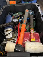 Top view of black bin containing various hardware and tools including the rubber mallets and air pressure gauge visible.