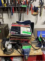 Photo showing Mastercraft angle grinder, Century battery charger box, and two mounted blue vices on workbench.