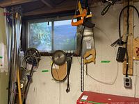 Photo showing hand saws, saw blades, and a few hanging hand tools on the wall including pipe wrenches and a vise grip.