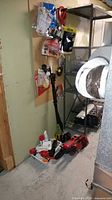 Photo shows a Black & Decker pole saw leaning against the wall on floor with a Royal hand vacuum and an auto edge trimmer in front on floor, with some hardware items visible in the background.