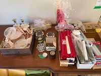 Overview of lot showing two silver-plated candle holders, glass votive holders, red and white stick candles, tea light candles, and other candle accessories on a wooden table.