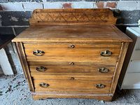 Front view of dresser showing three drawers, fluted pilasters, brass bail handles and carved backsplash