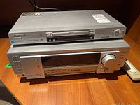 JVC RX-7042 audio/video receiver and Pioneer DV-578A DVD player stacked on wooden surface with remote beside them.