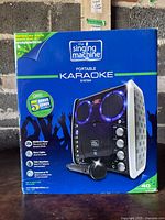 Front view of the sealed retail box for The Singing Machine portable karaoke system showing product image and features.