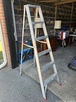 Side view of 6-foot folding aluminum ladder showing five wide foot rungs and red non-slip caps on feet.