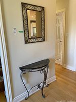 Wall mirror and matching hallway table positioned against cream wall near doorways in a home interior. Shows overall size and design.
