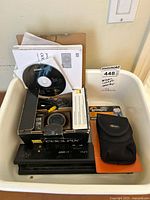 White plastic basin containing the Nikon Coolpix S8000 original box with accessories and a Lowepro camera bag