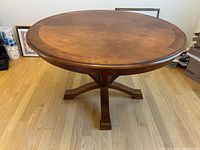 Front view of the round wooden table showing the top and base.