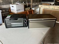 Photo of the toaster oven and bread box placed side by side on a table showing size and appearance.