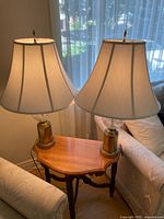 Two lamps positioned on a small wooden table between chairs, showing overall appearance and size relative to furniture.