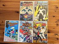 All five bagged and boarded comic books laid on table