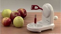 Apple peeler in use with apples for scale