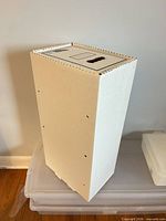 Perspective view of comic long box standing vertically, showing white exterior and side perforations