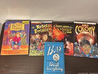 All five books front covers displayed on table