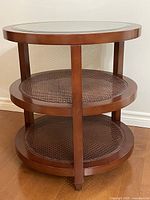 Full front view of round end table showing three tiers and glass top