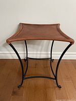 Full view of stool showing leather seat and iron legs