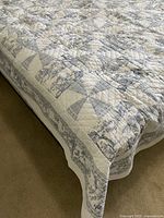 Quilt draped on bed showing toile border and pinwheel blocks