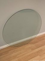 Full view of round glass tabletop leaning against wall