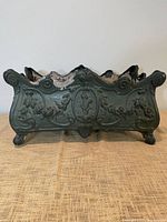 Front view of cast planter showing ornate relief and feet