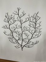 Full front view of metal branch wall art against white wall