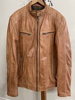 Front view of tan leather jacket on hanger showing overall condition