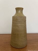Full front view of olive green textured pottery vase on wood surface