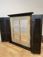 Mirror with shutters fully open showing six-pane mirror and black interior shutter finish