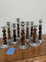 Front view of all nine candlesticks showing wood shafts and metal bases