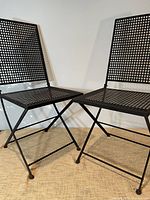 two black metal folding chairs full view